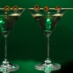 Two ominous looking martini glasses sit with an absinthe green background and a Mr. Yuk sticker